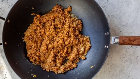 A black pan with quinoa fried rice in it.
