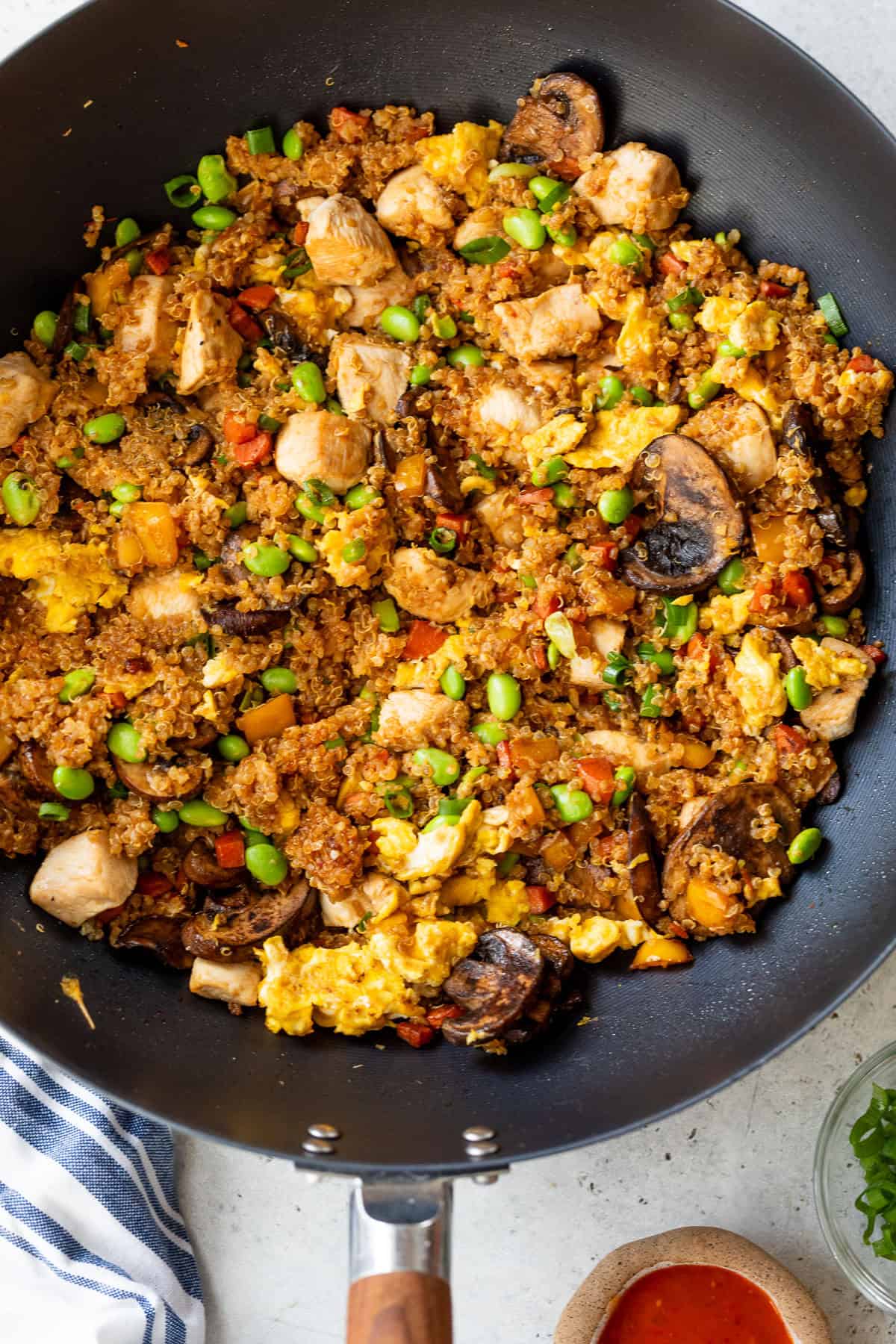 A pan filled with quinoa fried rice, vegetables, scrambled eggs, and mushrooms on a light countertop.