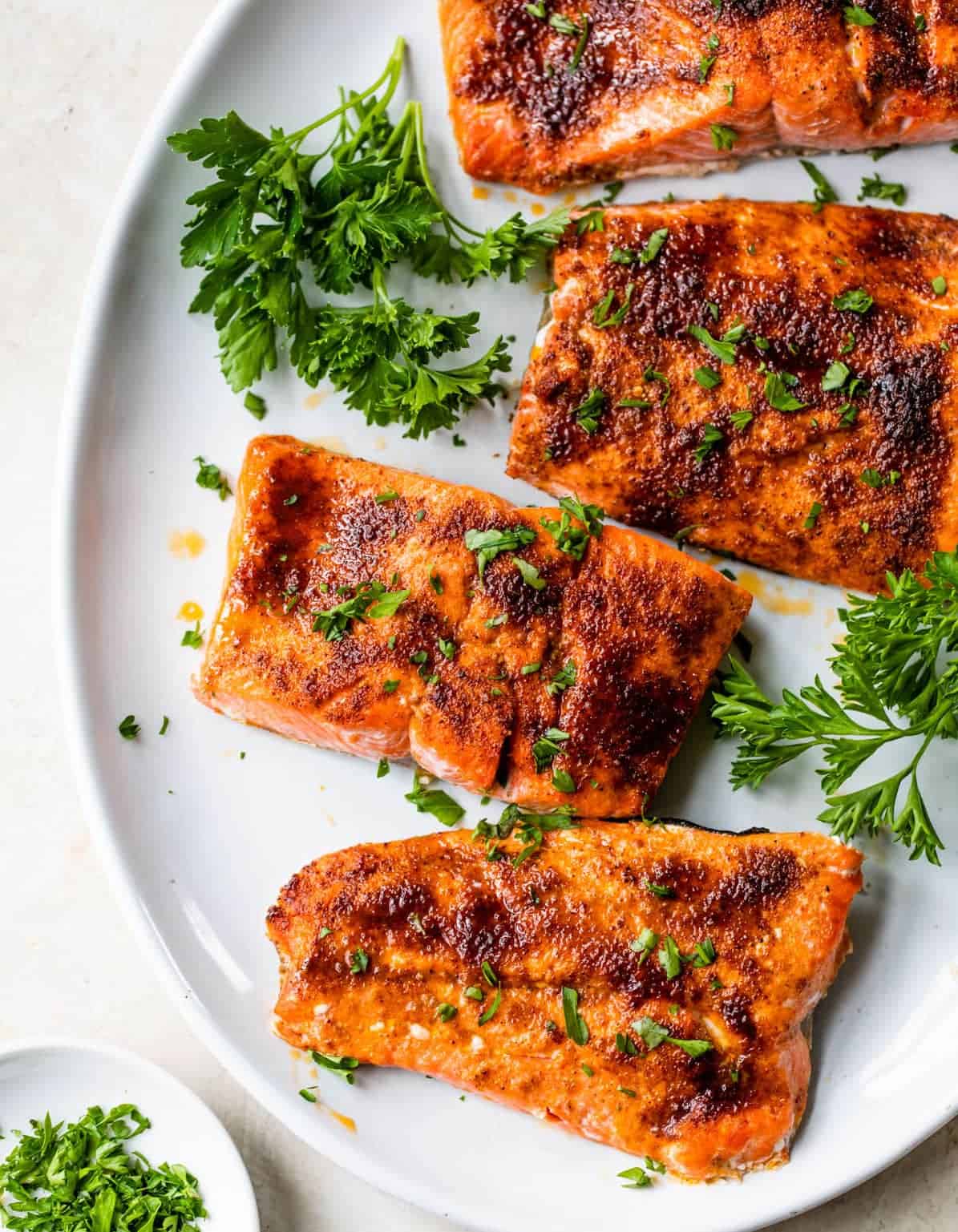 Broiled salmon with seasoning rub on platter with sprigs of parsley.