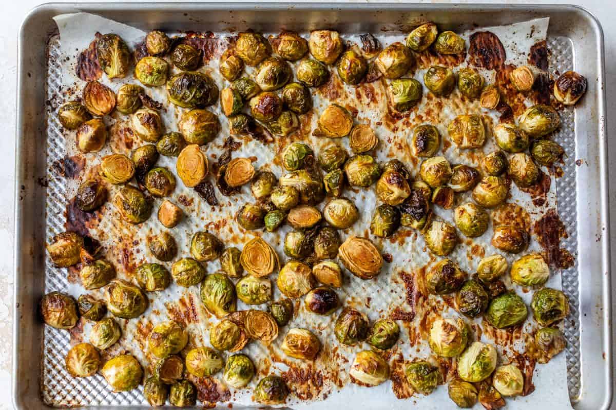Caramelized Brussels sprouts on a parchment-lined baking sheet, browned and caramelized after baking.