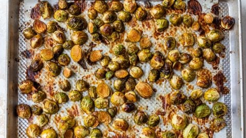 Caramelized Brussels sprouts on a parchment-lined baking sheet, browned and caramelized after baking.