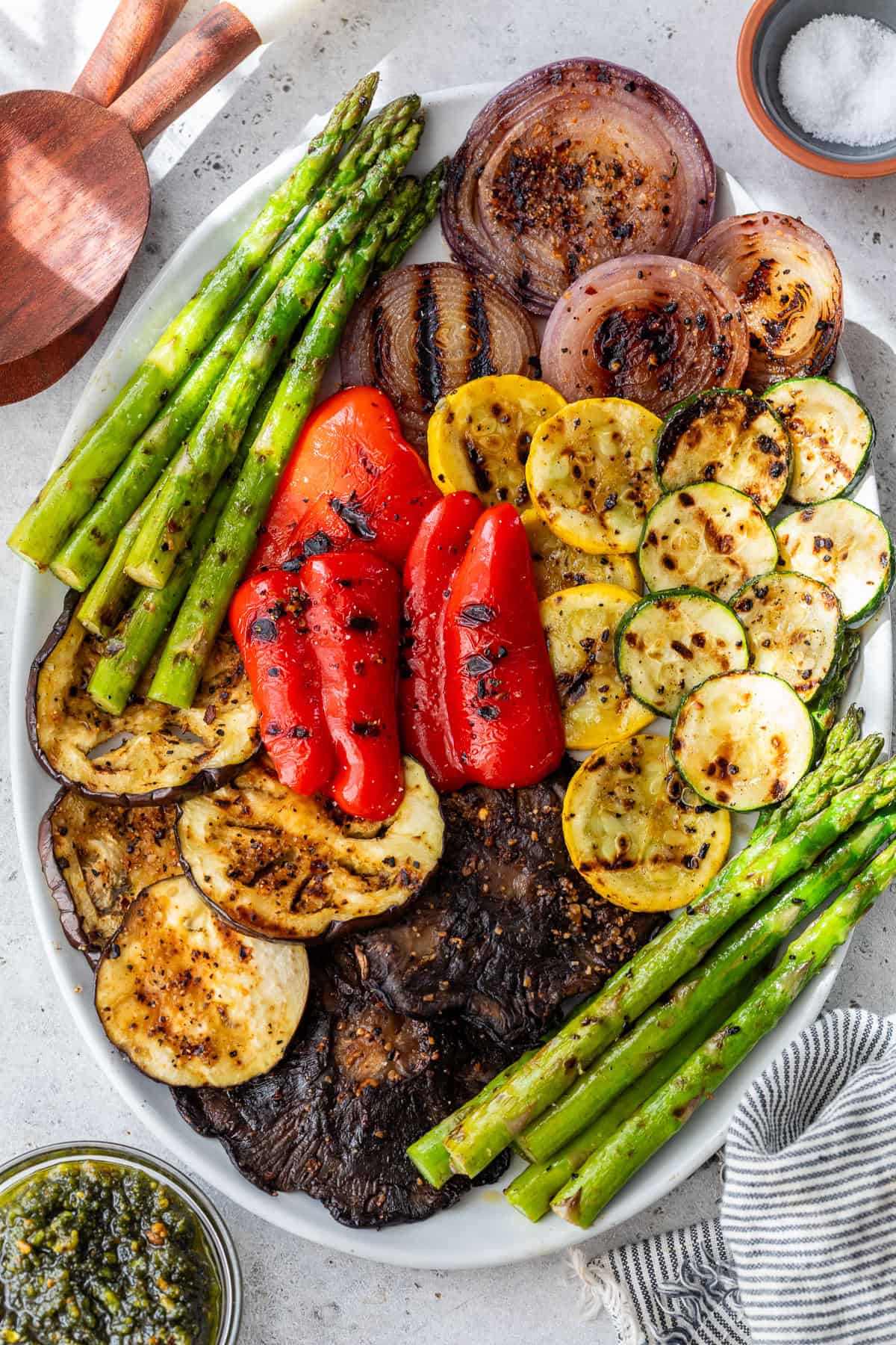 An oval platter with grilled vegetables, including asparagus, red onion, red pepper, zucchini, yellow squash, eggplant, and portobello mushrooms.
