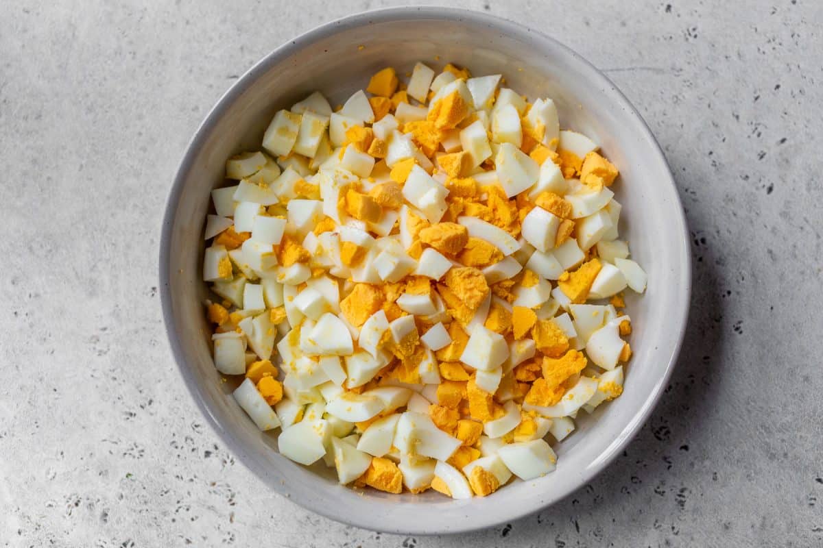 A bowl filled with chopped hard-boiled eggs, showing both the white and yellow yolk pieces.