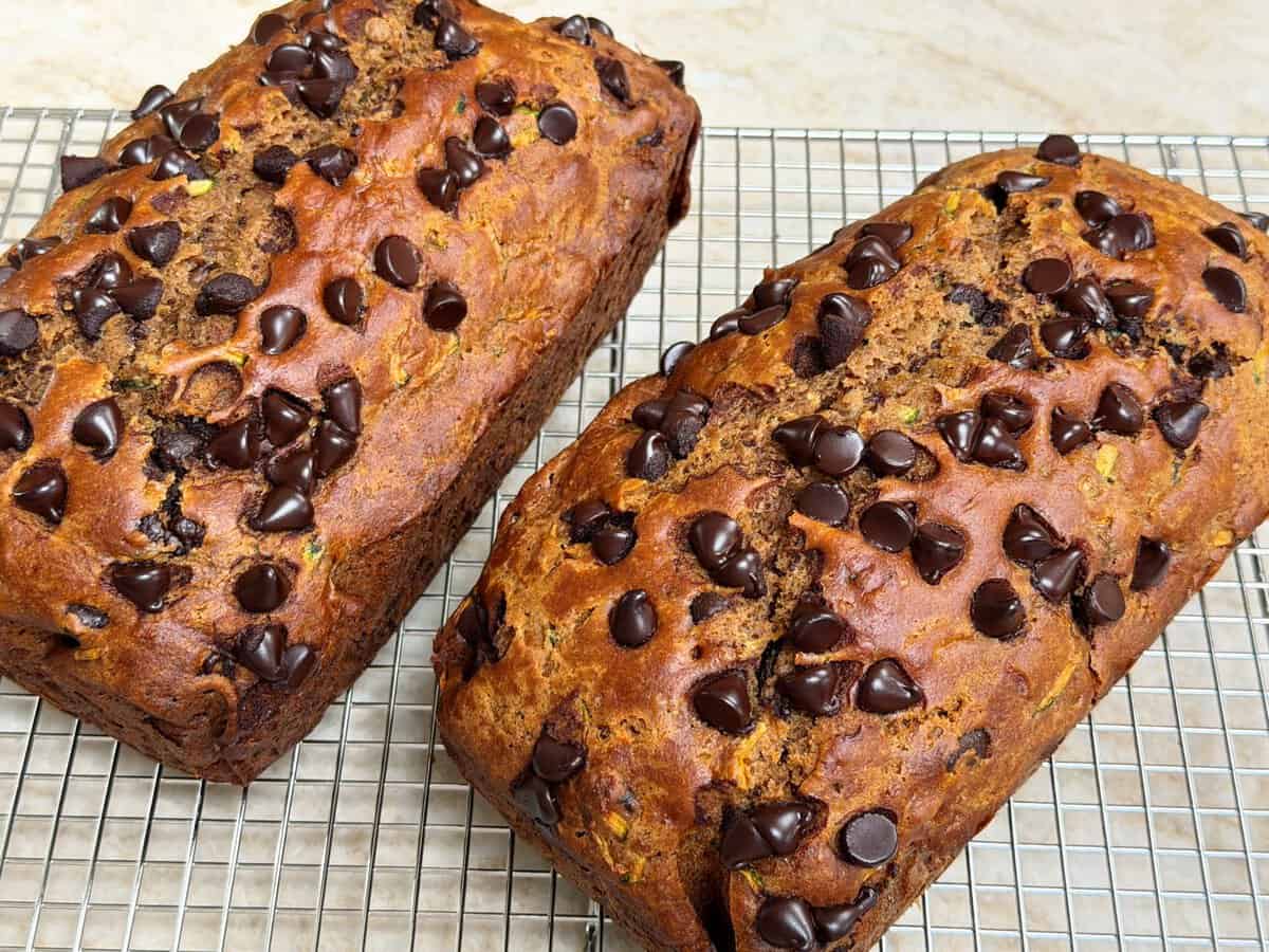 Two loaves of chocolate chip banana bread cooling on a wire rack.