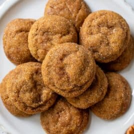A plate of round, sugar-coated pumpkin spice cookies arranged in a pile on a white plate.