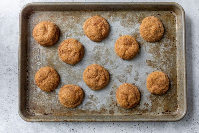 Ten pumpkin spice cookies arranged on a worn baking sheet, viewed from above.