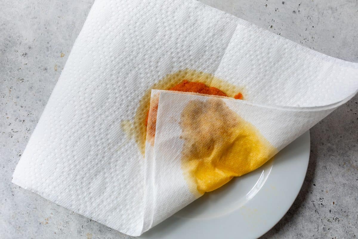 Paper towel blotting moisture from pumpkin puree spread onto plate.