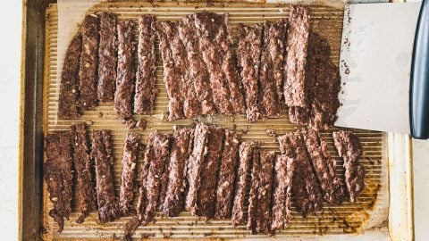 Sliced gyro meat on a baking sheet with a metal spatula on the right side.