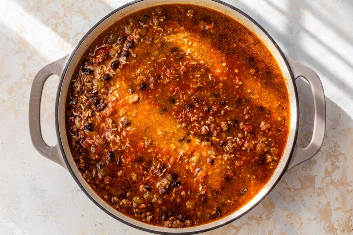 A pot with ground beef, black beans, rice, and tomatoes on a light countertop.