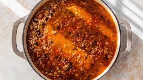 A pot with ground beef, black beans, rice, and tomatoes on a light countertop.