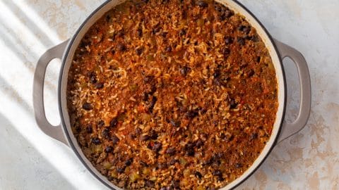 A pot of taco rice with cooked ground beef, black beans, rice, and vegetables in a tomato-based sauce.