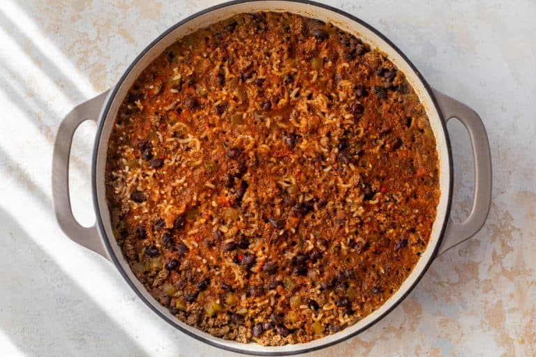 A pot of taco rice with cooked ground beef, black beans, rice, and vegetables in a tomato-based sauce.