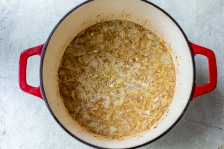 Chopped onions sautéing in a red enameled cast iron pot.